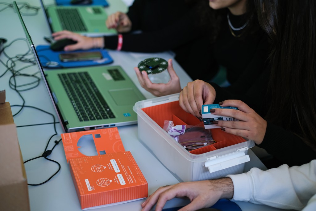 Close-up of multiple hands using the Arduino Explore IoT Kit and keyboards on a desk during usability testing session – Liam Aljundi